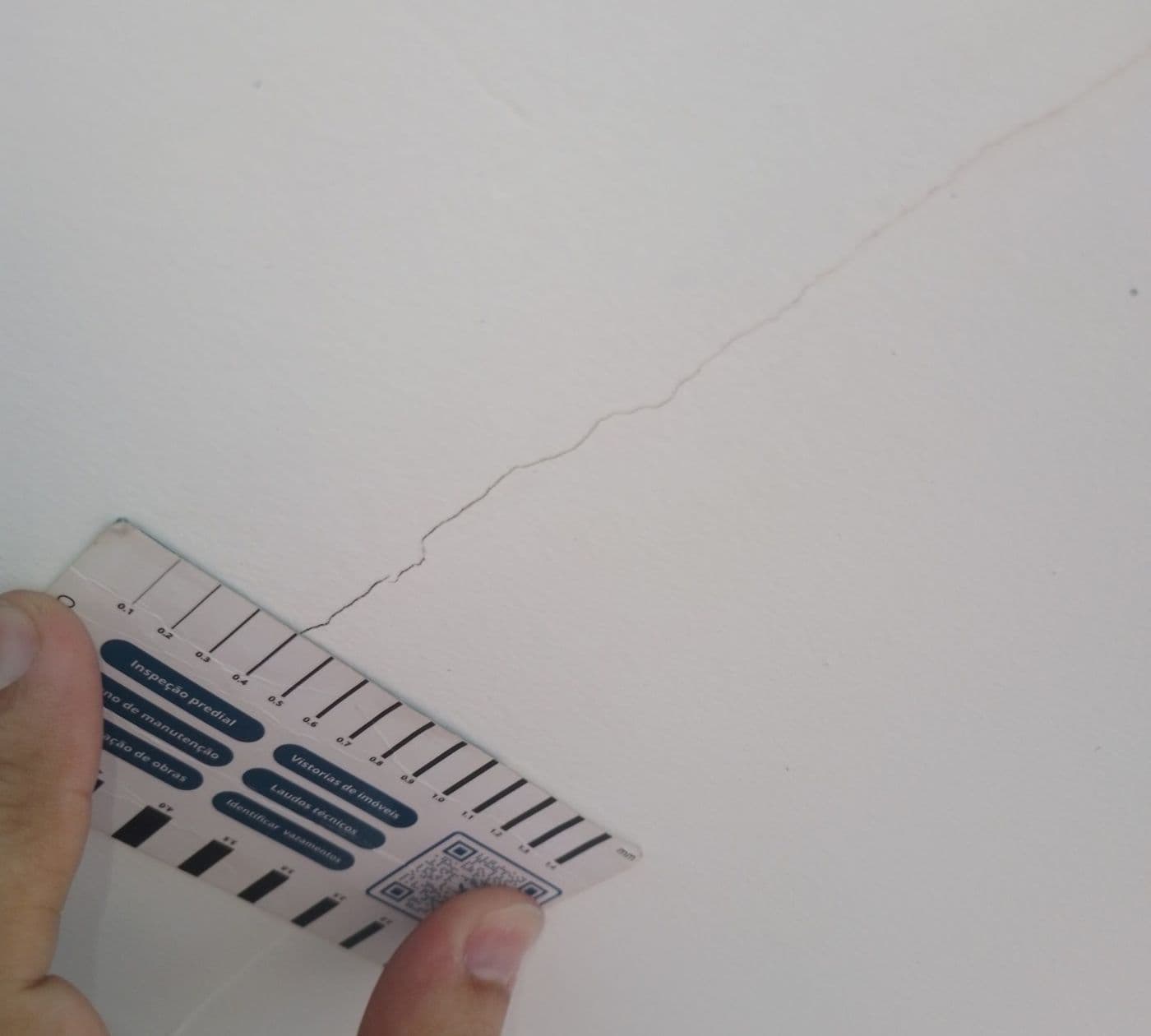 Engenheiro medindo fissura com fissurômetro durante a vistoria